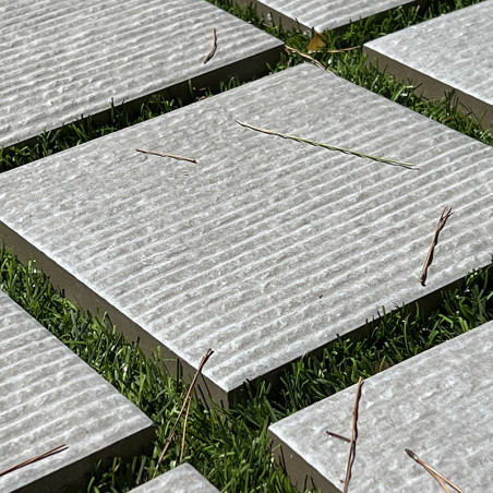 Los azulejos cuadrados de piedra se encuentran espaciados uniformemente sobre una exuberante hierba verde, con crestas texturiza
