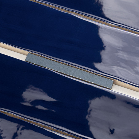 Los azulejos brillantes de color azul oscuro reflejan la luz y muestran una superficie lisa con una franja gris fina y texturiza