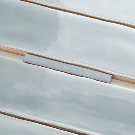 Les carreaux bleu clair brillants et allongés sont alignés en rangées parallèles, interrompues par un seul carreau gris rectangu