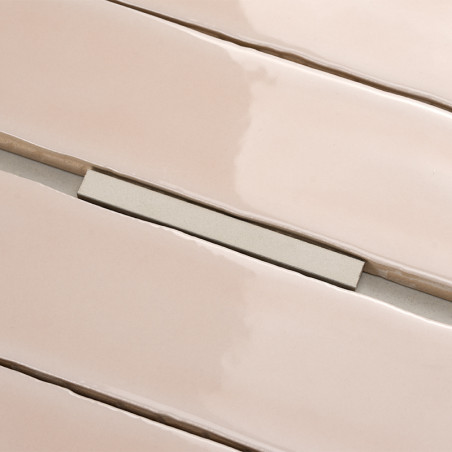 Glossy, rectangular beige tiles are aligned with narrow gaps, creating a sleek surface. A small spacer maintains consistent sepa