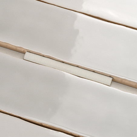 Les carreaux blancs rectangulaires brillants sont disposés en lignes parallèles, avec des lignes de coulis visibles les séparant
