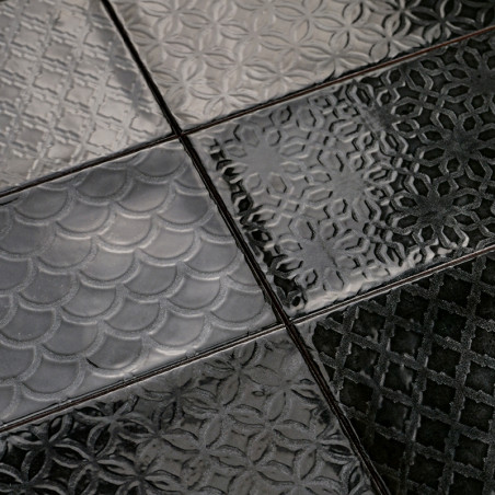 Les carreaux noirs et brillants présentent divers motifs en relief, notamment des écailles, des motifs floraux et des motifs géo