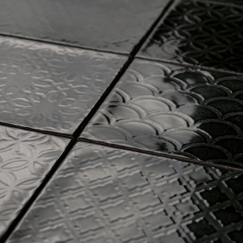 Glänzende Keramikfliesen zeigen geometrische Muster, darunter Kreise und Kreuze, und erzeugen eine strukturierte Oberfläche in v
