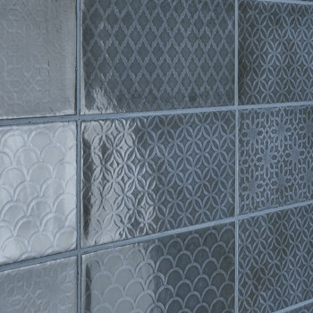 Neuf carreaux carrés avec des motifs géométriques texturés, notamment des motifs en losange, circulaires et festonnés, disposés 