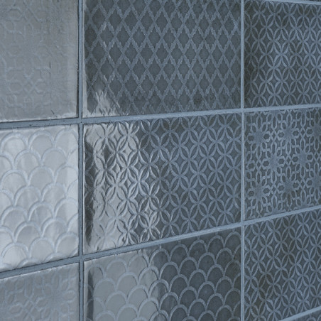 Nine square tiles with textured, geometric patterns, including diamond, circular, and scallop designs, arranged in a grid on a w