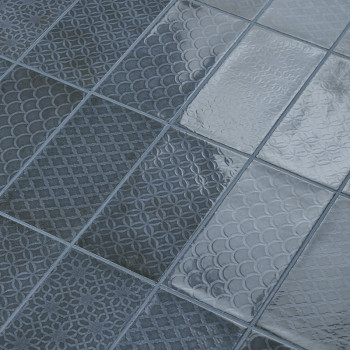 Grijze tegels tonen ingewikkelde, zich herhalende geometrische patronen, gerangschikt in een raster. Ze reflecteren het licht op