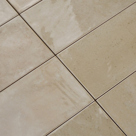 Les carreaux de céramique de couleur crème forment une grille réfléchissant doucement la lumière sur leurs surfaces brillantes. 