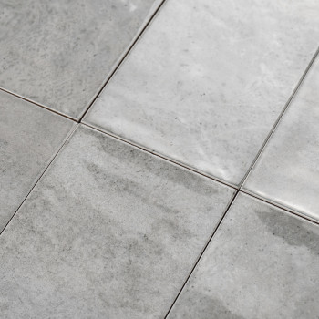 Ladrilhos cerâmicos cinza formam um padrão de grade, assentados de forma plana e uniformemente dispostos, apresentando uma super