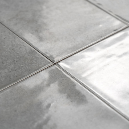 Los azulejos de cerámica grises se encuentran planas, reflejando la luz en su superficie brillante, con sutiles variaciones de t
