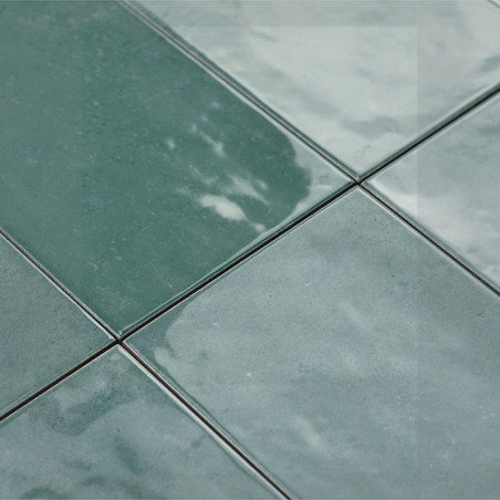 Los azulejos de cerámica verde aparecen brillantes bajo la luz, colocadas en forma de cuadrícula. Su superficie reflectante añad