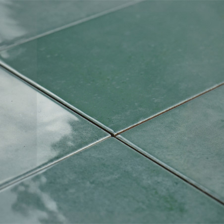 Cuatro azulejos verdes brillantes se encuentran en el centro, reflejando la luz y creando una superficie lisa y pulida en un amb