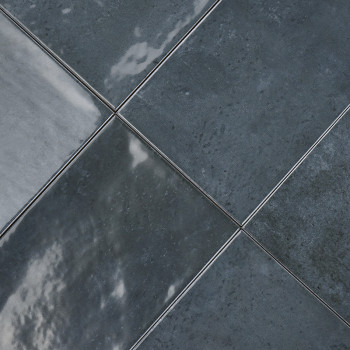 Os ladrilhos cerâmicos cinza escuro são alinhados diagonalmente, refletindo a luz sutilmente em suas superfícies brilhantes, cri