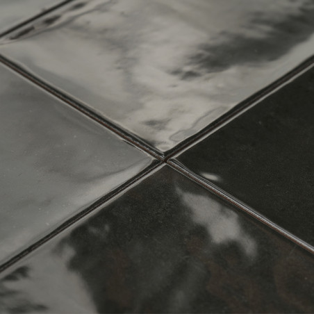 Les carreaux de céramique brillants et sombres s’assemblent parfaitement, reflétant une lumière douce. La surface semble lisse e