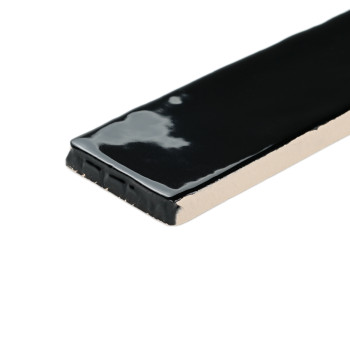 A rectangular tile with a glossy black surface reflects light, positioned against a plain, white background.