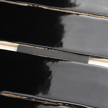 Les carreaux de céramique noirs brillants sont parallèles à de fines lignes de coulis beiges qui les séparent, reflétant un moti