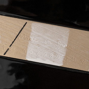 Un azulejo de cerámica negro presenta una franja central color canela con un texto en relieve que dice `Hecho en España` y númer
