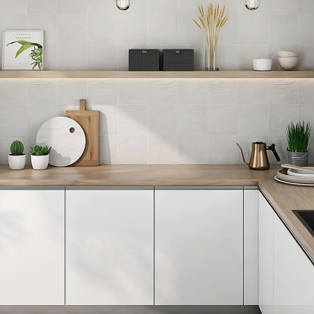 White kitchen cabinets sit below a light wood countertop, decorated with potted plants and utensils, beneath a wooden shelf disp