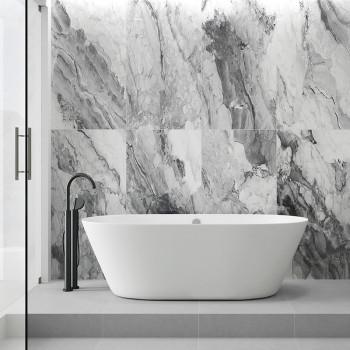 Een strak wit bad staat op een grijs platform, omgeven door muren met marmerpatronen en grijze en witte wervelingen, waardoor ee