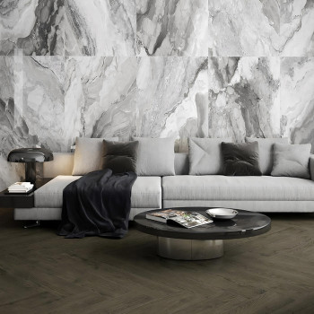 Een moderne woonkamer is voorzien van een lichtgrijze sofa versierd met donkere kussens. Ervoor staat een strakke tafel met tijd