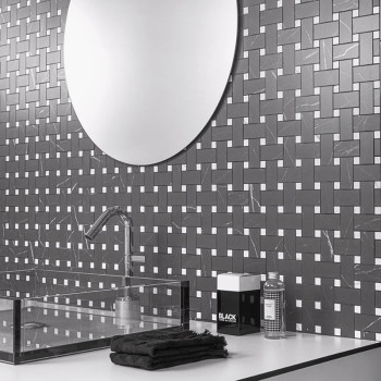 Een reflecterende ronde spiegel hangt boven een tegelwand met geometrisch patroon, met in elkaar grijpende zwarte tegels met wit