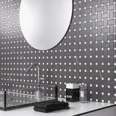 Un miroir circulaire réfléchissant est suspendu au-dessus d’un dosseret de carreaux à motifs géométriques, comportant des carrea