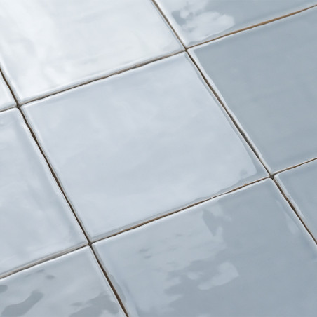 Carreaux de céramique carrés réfléchissant la lumière, disposés en grille. la surface apparaît brillante et lisse, créant un eff