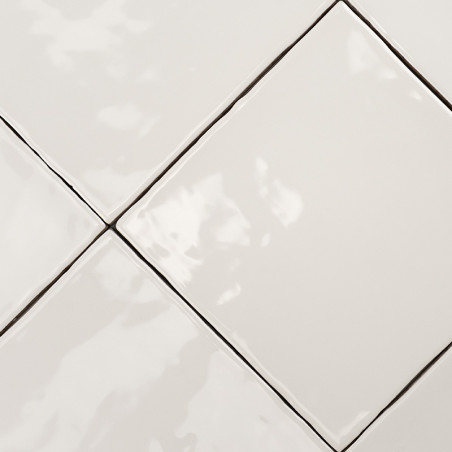 Los azulejos cuadrados de color blanco brillante están dispuestos en un patrón diagonal, creando una superficie lisa y reflectan