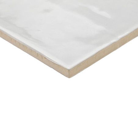 Un carreau de céramique blanc cassé brillant repose à plat, affichant une surface lisse avec de subtiles variations de texture. 