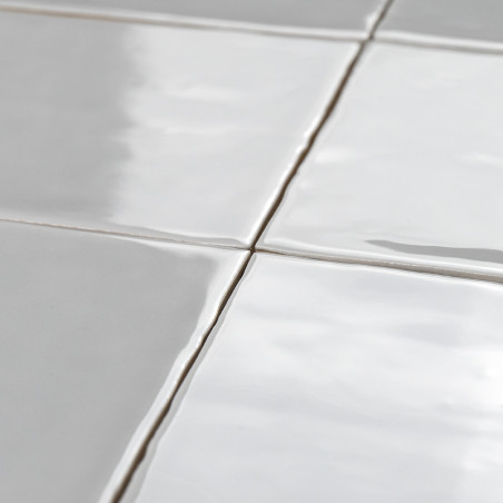 Les carreaux de céramique blanche forment une grille avec des lignes de coulis visibles, posées à plat et créant une surface élé