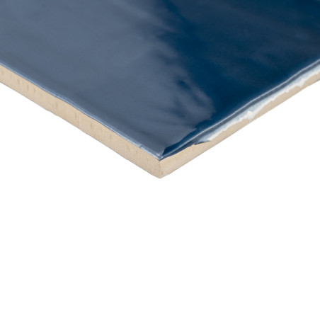 Un azulejo cerámico rectangular muestra una superficie brillante de color azul intenso. Sus bordes revelan una capa inferior de 