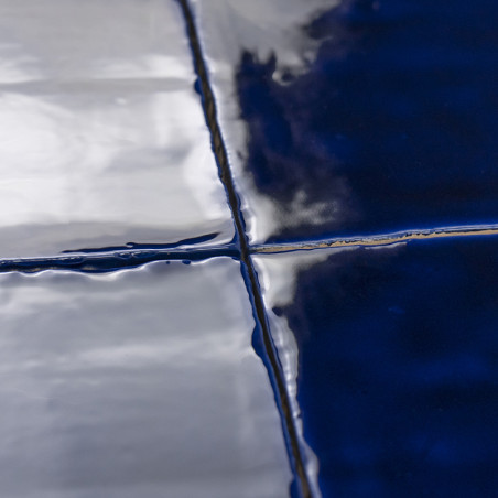 Les carreaux brillants d'un bleu profond reflètent la lumière et se croisent au niveau de lignes de coulis épurées. la surface l