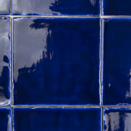 Glänzende, tiefblaue Fliesen bilden ein Gittermuster. Die Fliesen erscheinen reflektierend mit leichten Variationen in Farbton u