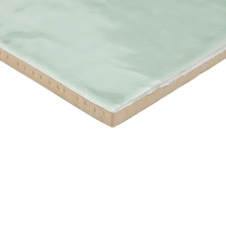 Eine quadratische Keramikfliese mit einer glänzenden, hellgrünen Oberfläche ruht auf einem schlichten weißen Hintergrund und zei Eine quadratische Keramikfliese mit einer glänzenden, hellgrünen Oberfläche ruht auf einem schlichten weißen Hintergrund und zei