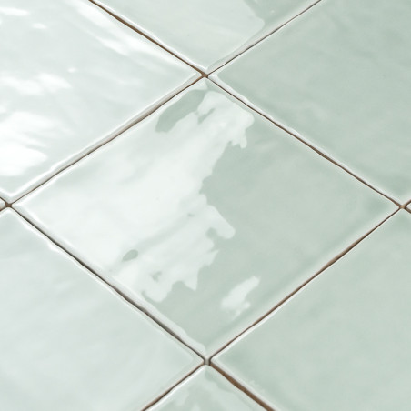 azulejos cerámicos cuadradas que reflejan la luz, dispuestas en diagonal en forma de cuadrícula, mostrando un color verde pálido