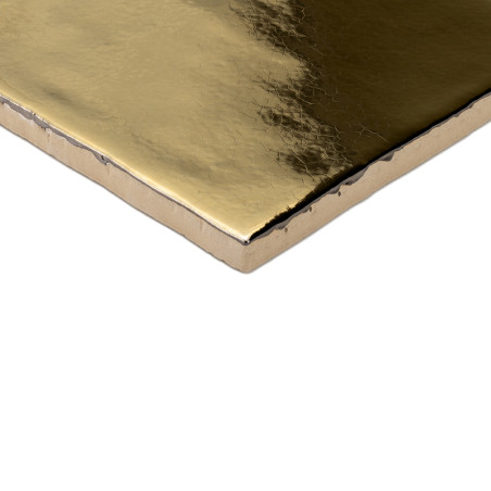 Een gouden, glanzende tegel met een licht gestructureerd oppervlak rust tegen een witte achtergrond en reflecteert licht met een