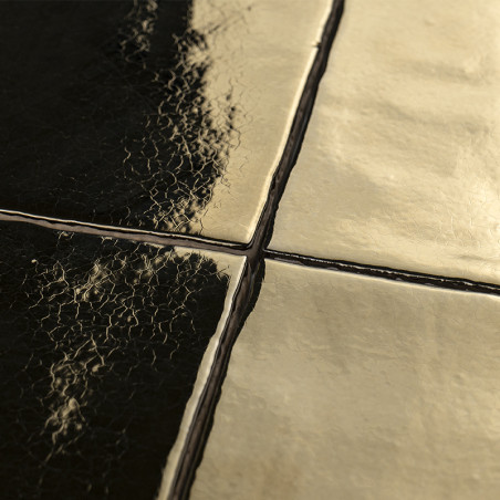 Vier glasierte Fliesen kreuzen sich in einer Nahaufnahme, mit einer knisternden Textur auf den dunklen Fliesen und einer glatten