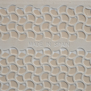 Keramische tegels met reliëf hebben een repetitief gebogen schubbenpatroon. de woorden `MADE IN SPAIN` staan ​​centraal in het o