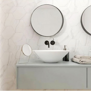 Un espejo redondo cuelga de la pared de un baño, encima de un moderno lavabo blanco. El ambiente incluye una decoración minimali
