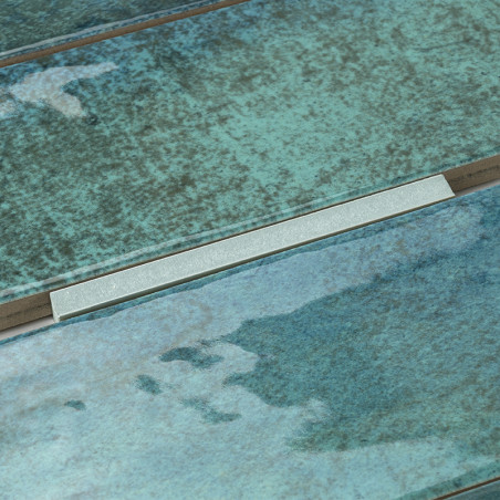 Les carreaux de céramique verts et bleus présentent une surface texturée réfléchissant la lumière. Il est disposé contextuelleme