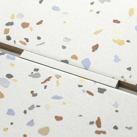 O ladrilho salpicado, exibindo manchas coloridas espalhadas, fica ao lado de outro ladrilho com uma linha reta de argamassa visí