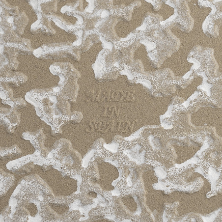 Die Fliese weist ein strukturiertes, wellenförmiges Muster mit Beige- und Weißmischungen auf. Der geprägte Text in der Mitte lau