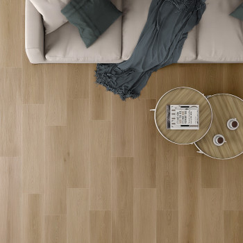 Een beige bank met blauwgroen kussens staat naast een houten salontafel op een lichte houten vloer, waardoor een gezellige woonk