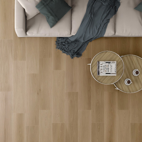 Een beige bank met blauwgroen kussens staat naast een houten salontafel op een lichte houten vloer, waardoor een gezellige woonk