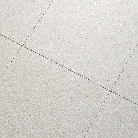 Les carreaux de pierre grise sont alignés selon un motif en grille, formant une surface de sol lisse et uniforme. De fines ligne