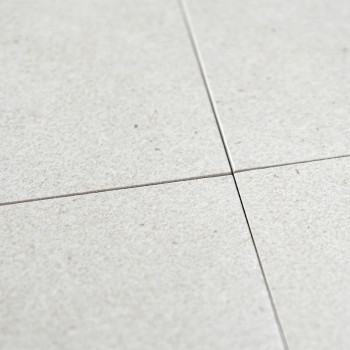 Four light gray ceramic tiles intersect at their corners, forming a cross pattern. The surface has a subtle, textured finish, su