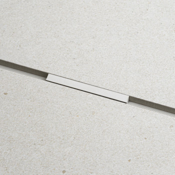 Un carreau rectangulaire repose fermement, séparé par d'étroites lignes de coulis sombres, sur une surface lisse et beige clair,