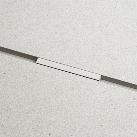 Un carreau rectangulaire repose fermement, séparé par d'étroites lignes de coulis sombres, sur une surface lisse et beige clair,