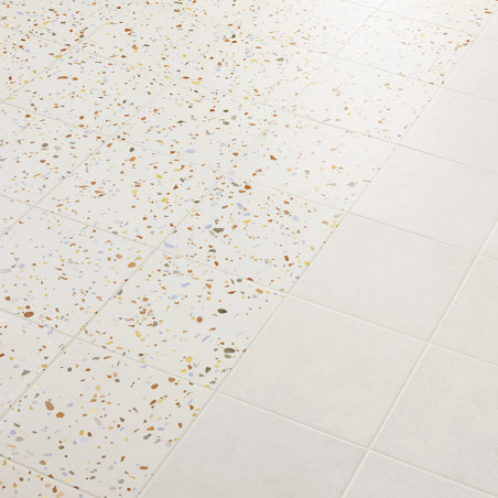 Die Fliesen gehen von Terrazzo, gesprenkelt mit mehrfarbigen Splittern, zu schlichtem Weiß über und erzeugen ein Muster auf der Die Fliesen gehen von Terrazzo, gesprenkelt mit mehrfarbigen Splittern, zu schlichtem Weiß über und erzeugen ein Muster auf der